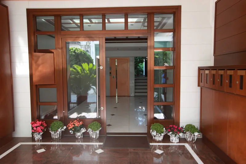 The glass entrance of Kallisti Apartments, with flowers on either side